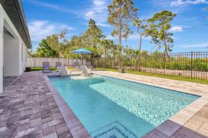 a swimming pool with chairs and an umbrella at Luxury Retreat in Secret Paradise in Bonita Springs