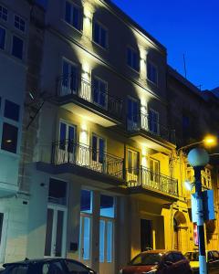 een gebouw met balkons en auto's die ervoor geparkeerd staan bij The Central guesthouse in Tal-Pietà