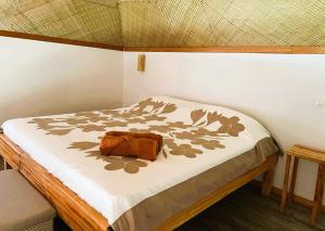 a bed with a brown pillow on top of it at Bungalow Miri in Tevaitoa