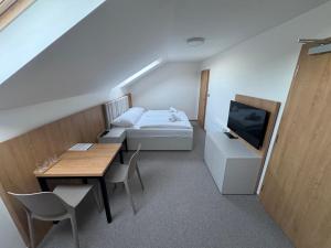Kleines Zimmer mit einem Bett, einem Tisch und einem TV. in der Unterkunft Eden Pálava, Penzion & Restaurant in Klentnice