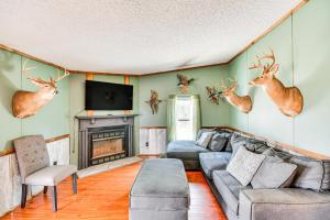 uma sala de estar com um sofá e cabeças de veado na parede em Rustic Union Springs Home with Gas Grill and Deck! 