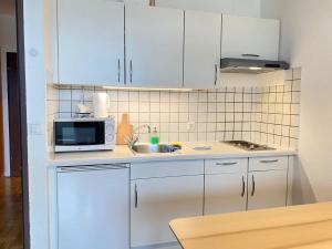 cocina con armarios blancos, fregadero y microondas en Bright Studio with View en Innsbruck