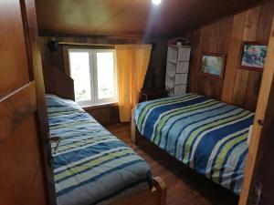 two beds in a room with a window at Cabañas Buen Recuerdo in Puyehue