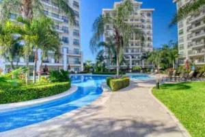 - une piscine bordée de palmiers et de bâtiments dans l'établissement Elegant Oceanview Penthouse - Steps from Jaco Beach & Nightlife, à Jacó