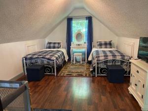 a attic room with two beds and a window at Dogwood Mountain House in Fancy Gap