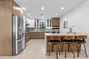 una cocina con nevera de acero inoxidable y armarios de madera en Luxe Pool - FirePit - Walk 2 Brickell Dining &Bars, en Miami