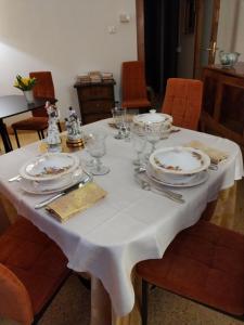 una mesa blanca con platos y vasos. en Bed & Breakfast Costanza4, en Scanno