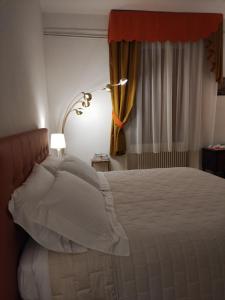 a bedroom with a bed with white pillows and a lamp at Bed & Breakfast Costanza4 in Scanno