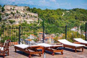 a group of chairs and tables on a balcony with a mountain at Dreamview & heated pool at Lucija 1 in Novigrad Dalmatia