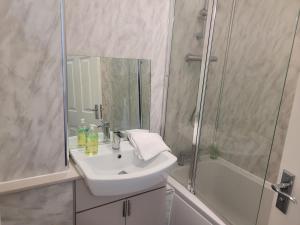 y baño blanco con lavabo y ducha. en RentUnique Nimrod House 2 bed ample parking en Crawley