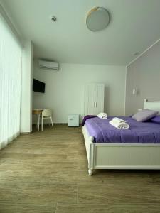 een slaapkamer met een bed met paarse lakens en een tafel bij Molo '93 - RoomsAndSea in Belvedere Marittimo