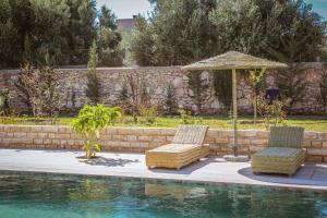 Villa OutMama charme & comfort في الصويرة: كرسيين ومظله بجانب مسبح