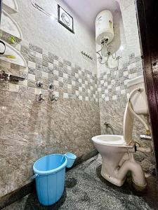 a bathroom with a toilet and a blue bucket at Cozy 2bhk near Manipal Hospital Dwarka in New Delhi