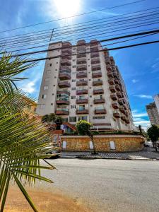 Vila BalneáriaにあるApto com WiFi a 140 metros da Praia do Caicara SPのヤシの木が目の前にそびえる白い高い建物