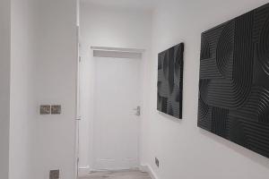 3 Bedroom, 3 Bathroom, Modern Apartment, Leicester في ليستر: ممر مع باب وصورتين على الحائط