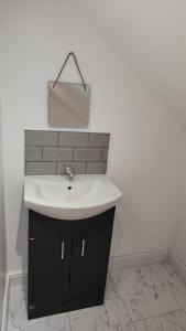 3 Bedroom, 3 Bathroom, Modern Apartment, Leicester في ليستر: حمام مع حوض أبيض وخزانة سوداء