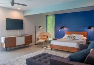 um quarto com uma cama, uma televisão e um sofá em Lost Oasis - A Ryson Property em Palm Springs