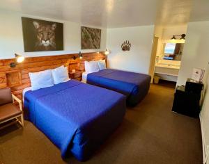 a hotel room with two beds with blue sheets at Red Bear Inn in Ennis