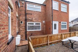 a brick house with a wooden fence and a patio at Lily Rose in Bedlington