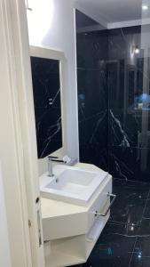 W łazience znajduje się biała umywalka i lustro. w obiekcie Garden Relais Le Fontanelle w mieście Montescudaio