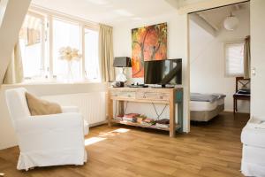 ein Wohnzimmer mit einem TV und einem weißen Stuhl in der Unterkunft B & B Villa Suisse in Scheveningen