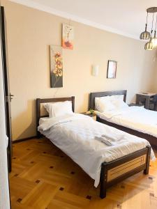 two beds in a room with wooden floors at Hotel Villa in Tbilisi City