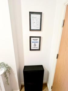 a black trash can in a hallway with two pictures on the wall at Stylish + Peaceful 2 bed/2bath in Slades Green
