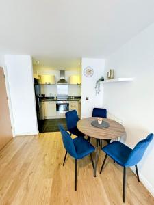 a dining room with a table and blue chairs at Stylish + Peaceful 2 bed/2bath in Slades Green