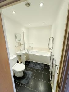 a bathroom with a toilet and a tub and a sink at Stylish + Peaceful 2 bed/2bath in Slades Green