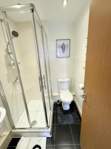 a bathroom with a toilet and a glass shower at Stylish + Peaceful 2 bed/2bath in Slades Green