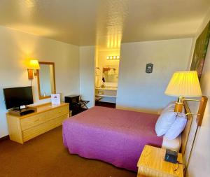 een hotelkamer met een bed en een televisie bij Red Bear Inn in Ennis