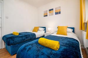 Duas camas num quarto com lençóis azuis e almofadas amarelas em Luxurious 2 bed house - Free Parking em Thamesmead