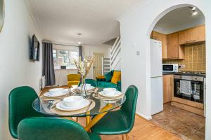 a kitchen and dining room with a table and green chairs at Luxurious 2 bed house - Free Parking in Thamesmead