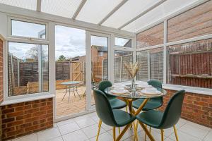 a dining room with a table and green chairs at Luxurious 2 bed house - Free Parking in Thamesmead