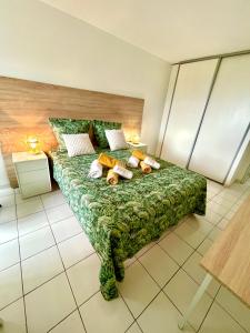 een slaapkamer met een groen bed met kussens erop bij Appartement de la Mer et du Levant in Schœlcher