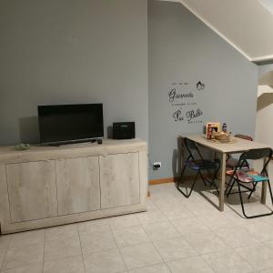 una sala de estar con TV en un armario y una mesa en House IL CORALLO, en Castrezatto