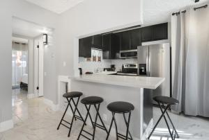 eine weiße Küche mit schwarzen Schränken und Barhockern in der Unterkunft Simple Elegance - A Ryson Property in Indio