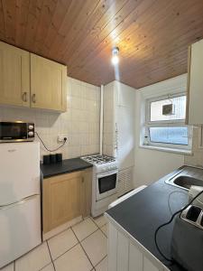 ロンドンにある1 bedroom flat in Whitechapel, Londonの木製の天井、白い家電製品付きのキッチン