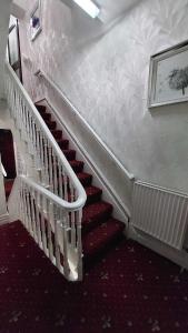ブラックプールにあるRockDeneの白い手すりと赤い絨毯が敷かれた階段