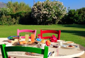 a table with breakfast food on it with two chairs at Garden Hotel Alghero in Fertilia