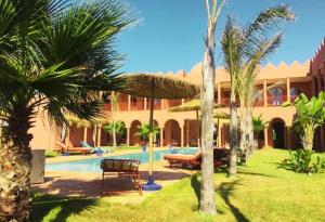 a resort with a swimming pool and palm trees at Dar De Santis in Azemmour