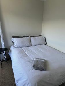 a white bed with a gray pillow on it at Hilltop Cottage in Taupo