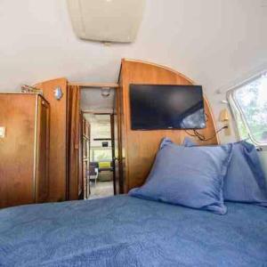 a bedroom with a blue bed with a wooden head board at Airstream at a Petting Zoo w/ Hot Tub in Sugar Grove