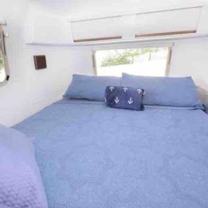 a bedroom with a blue bed with blue pillows at Airstream at a Petting Zoo w/ Hot Tub in Sugar Grove