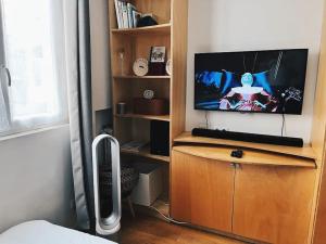 a tv sitting on a wooden stand in a room at Sunny - Studio confortable près de la Tour Eiffel in Paris