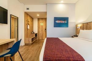 a hotel room with a bed and a desk and chairs at Hotel Distrito ZF By OxoHotel in Bogotá