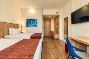 a hotel room with two beds and a flat screen tv at Hotel Distrito ZF By OxoHotel in Bogotá +30 photos