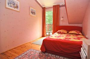 a bedroom with a red bed and a window at Domek Leśny in Poddąbie