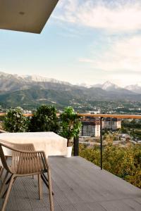 a chair sitting on a balcony with a view of mountains at Уютный домик для идеального отдыха in Almaty