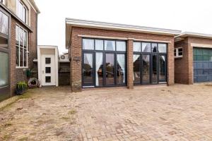 een stenen huis met glazen deuren op een oprit bij De Loods in Kampen